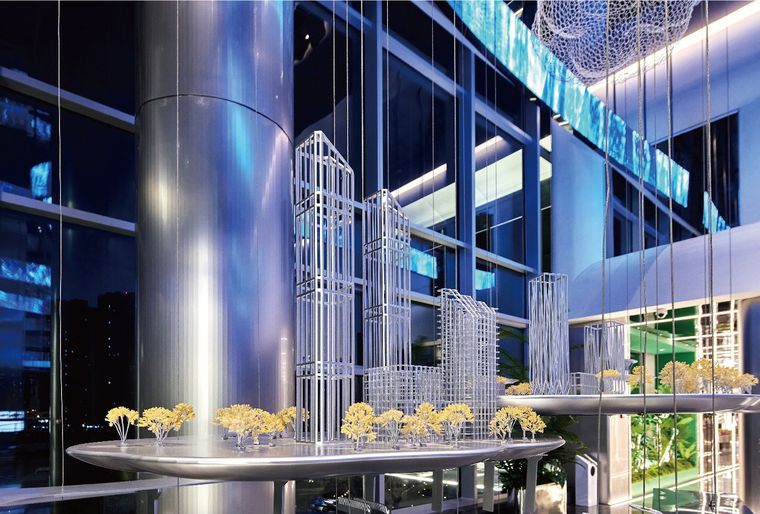 Suspended art installation of a transparent tower model in a tall glass lobby