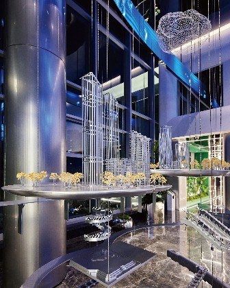 Suspended crystal city model in a glass lobby under blue light