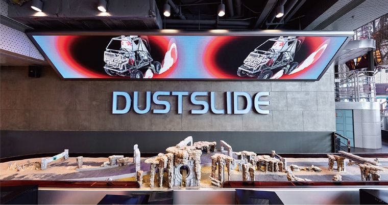 Interactive display with a racing track and desert scene under a wide screen
