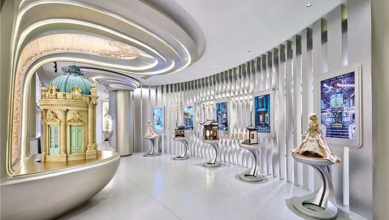 White exhibition corridor with curved ceilings and models on individual plinths