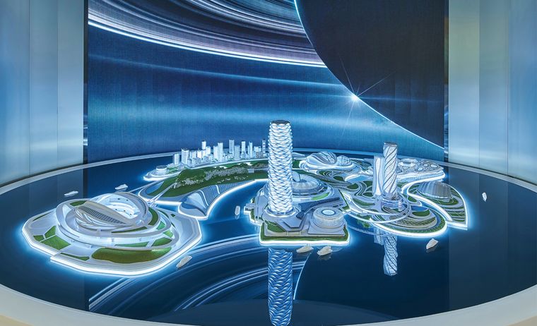 Exhibition hall with project models on white platforms and information screens