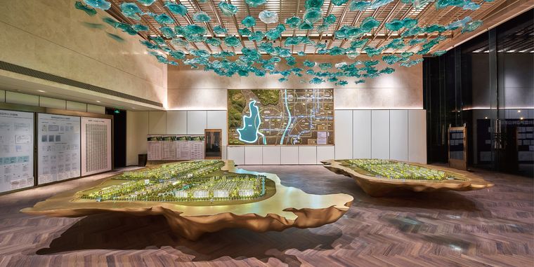Exhibition hall with two terrain models under a patterned ceiling