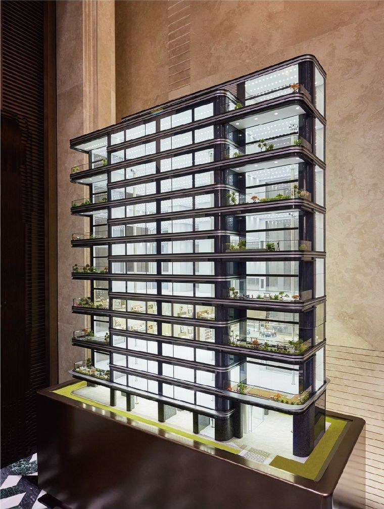 Model of a residential tower with planted balconies on every floor, before a marble column