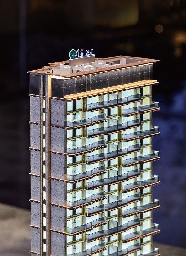 Model of a residential tower lit at night with the project mark on the roof