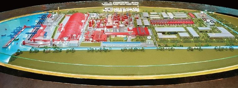 Model of a coastal industrial complex with red buildings and a loading quay