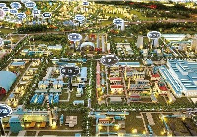 Model of an industrial city lit at night with labels for each zone
