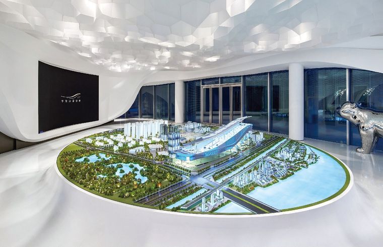 Curved white exhibition hall with a project model on a circular platform