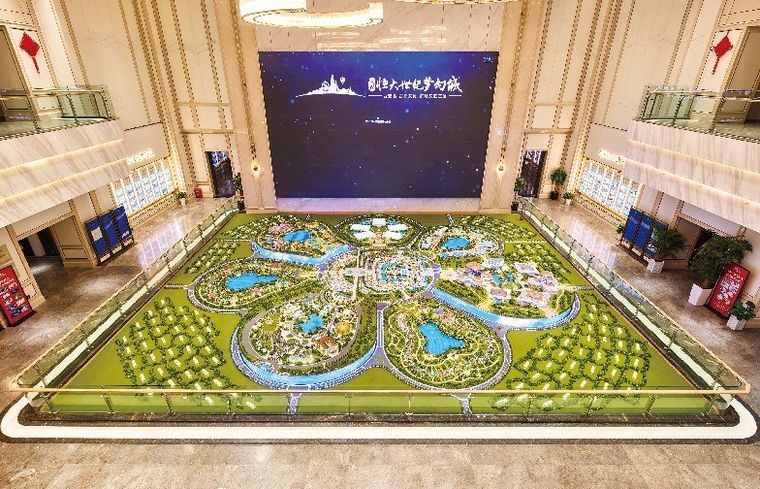 Model of a leisure city extending through a large hall before a display screen