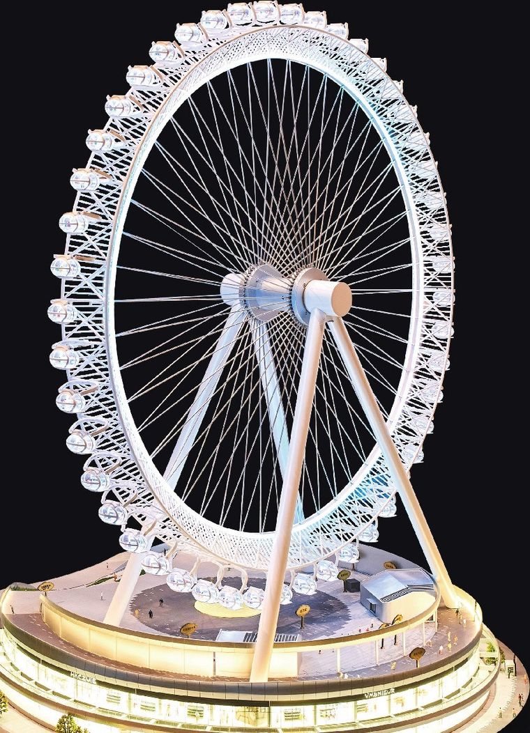 Model of a large Ferris wheel on a lit base against a black ground