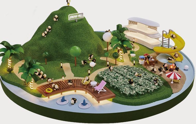 Model of a children's play area with a green mound and slides on a circular base