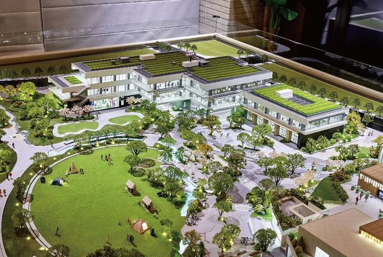 Model of an amenity building with green roofs and a wide park in front