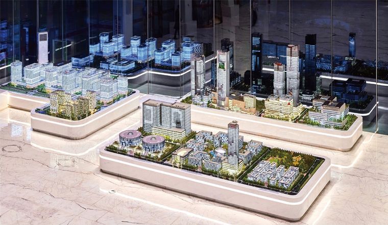 Two adjacent models of a business complex and its urban setting on oval bases