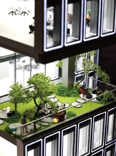 Cutaway model revealing an internal garden and furnished offices behind the facade