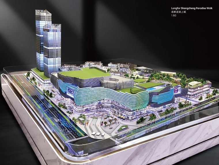 Model of a retail and office complex lit at night on a marble base