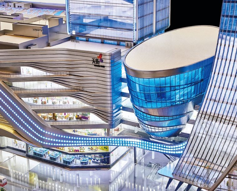Close view of a shopping centre model with a flowing facade and lit atria