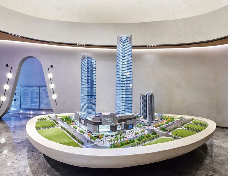 Model of two towers and a shopping centre on an oval platform in a curved showroom