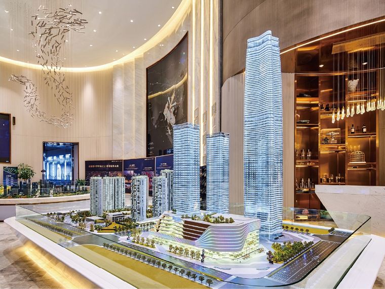 Office tower model on a circular platform in a white showroom