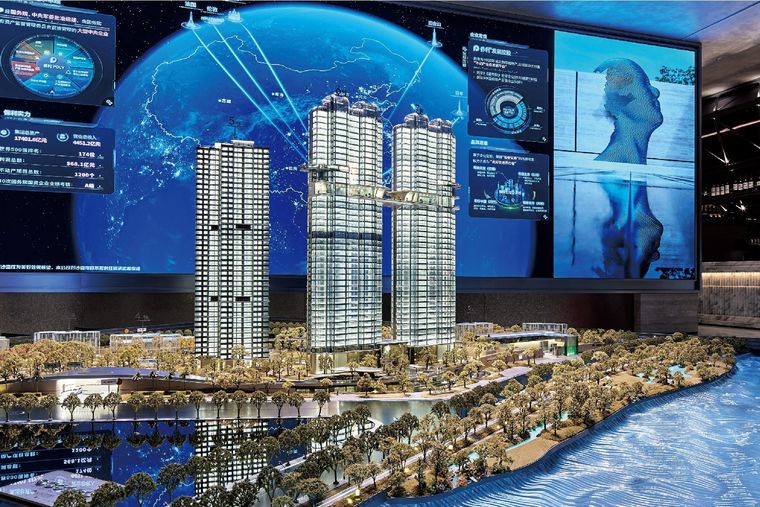 Model of two residential towers on a waterfront before an information screen wall