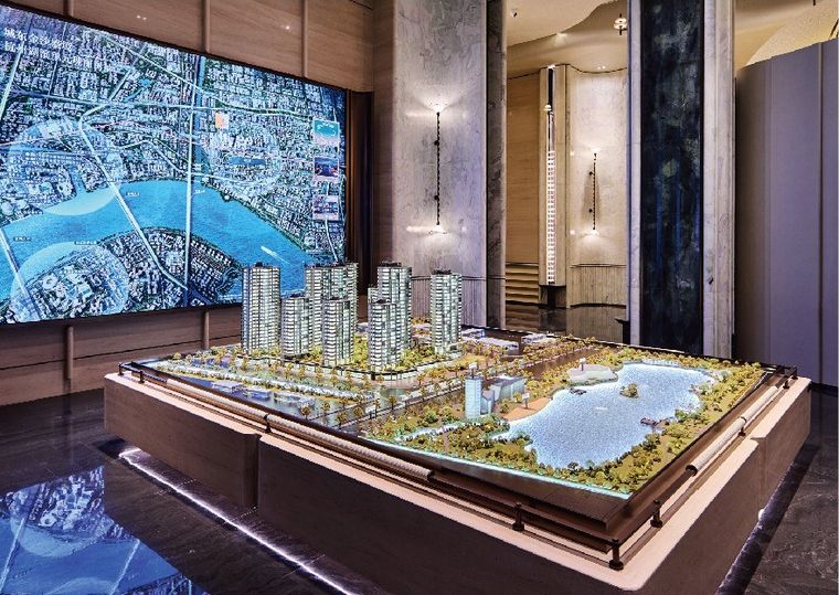 Model of a residential project before a large map screen in a sales gallery