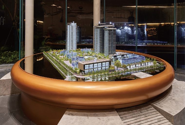 Model of a residential complex on a circular copper base in a glass lobby
