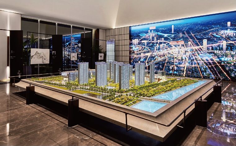 Model of a residential project before a night-city screen in a sales gallery