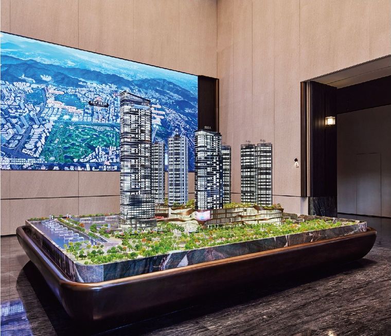 Model of residential towers on a dark base before a photographic wall