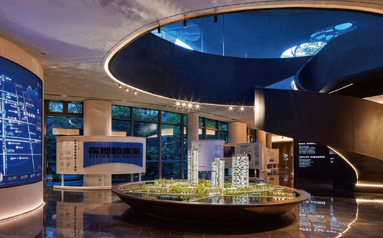Model of a residential project in a lobby under a lit oval ceiling