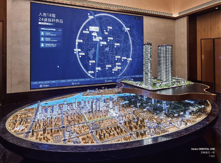 Model of a city and a residential tower before an interactive map screen