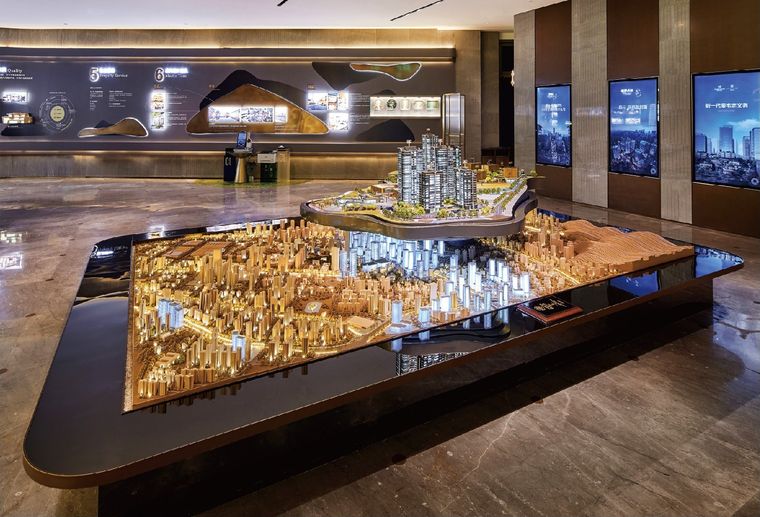 Model of a city extending along a black table before information screens