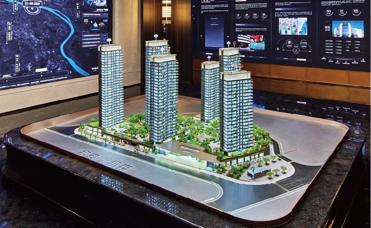 Model of residential towers on a marble base before a screen wall