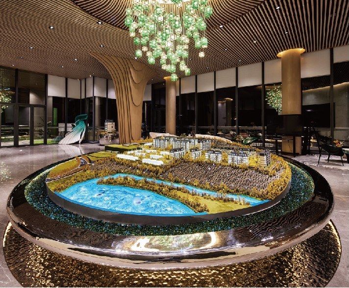 Model of a residential project on a circular base beneath a large chandelier