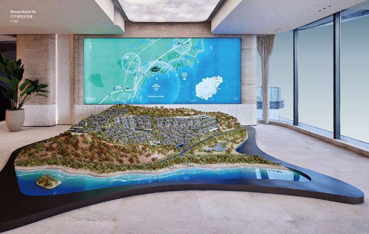 Model of a residential peninsula before a map screen in a glass lobby