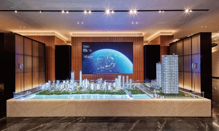 Model of a residential project before an astronomical screen in a timber-lined hall