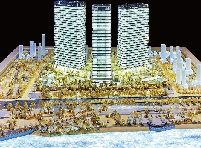 Model of three residential towers with the city behind on a dark base