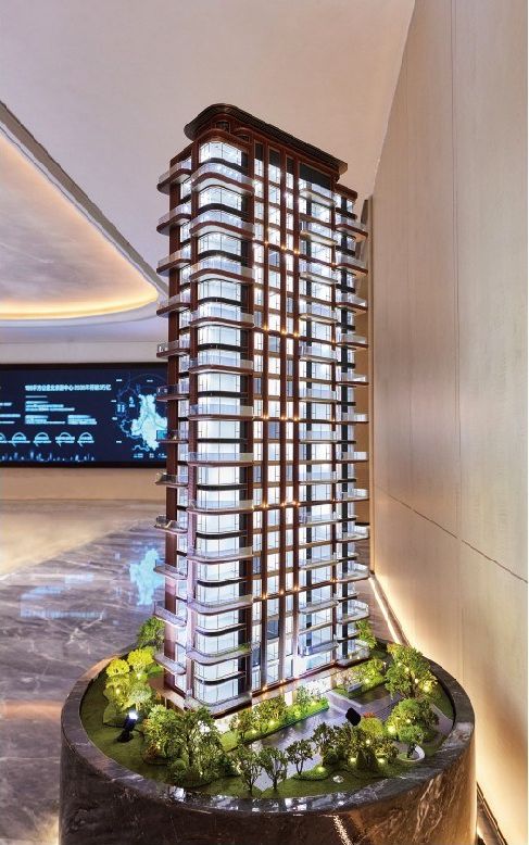Model of a slender residential tower on a marble base before a screen