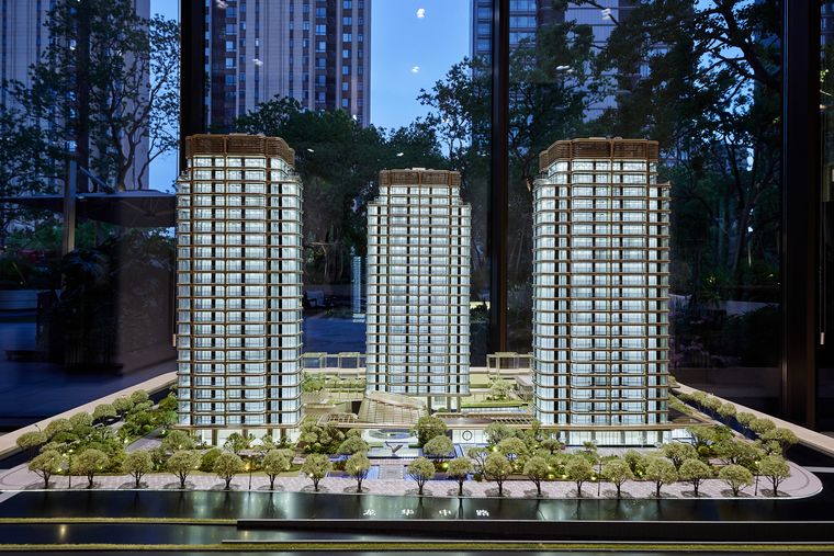 Three residential towers among dense planting on a display base