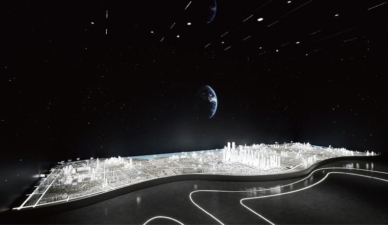 Model of a coastal city lit in a darkened hall against a space backdrop