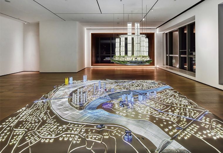 Model of a river city spread across a timber exhibition floor with floor lighting