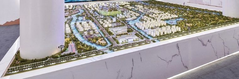 Model of a city master plan before a red display wall in a hall with white columns