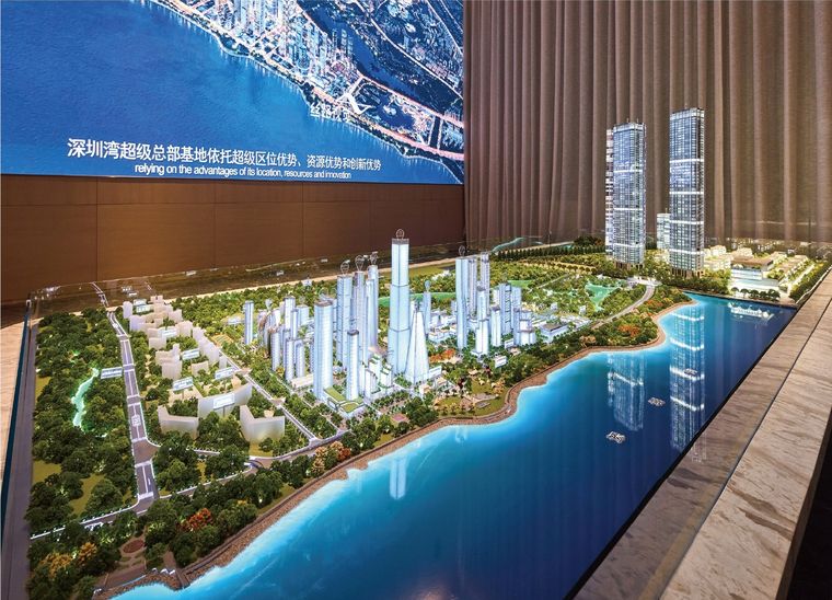 Model of a bay frontage with towers and a marina before a photographic wall
