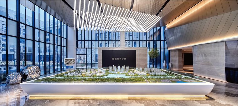 Model of a project on a curved white platform in a tall glass lobby
