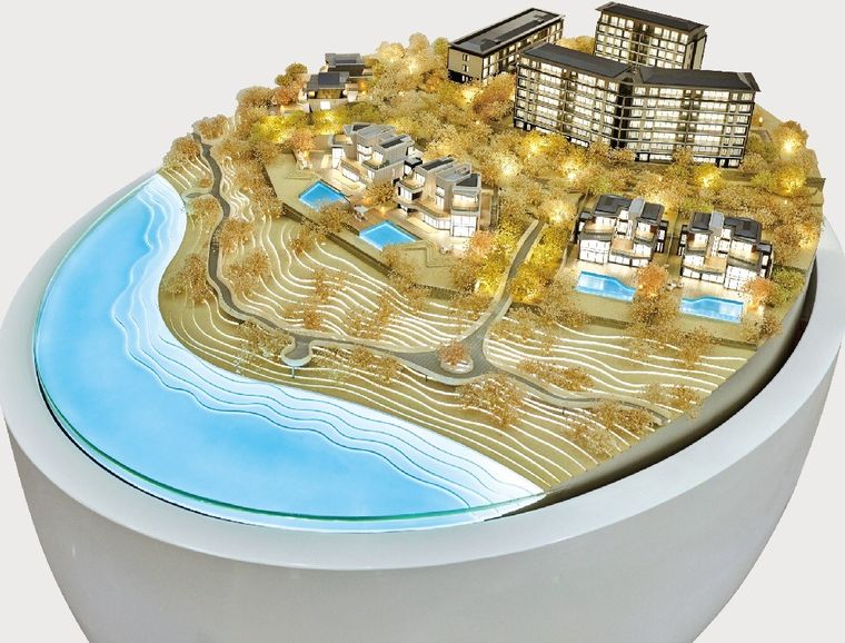 Model of a residential resort on a coastal slope under golden light