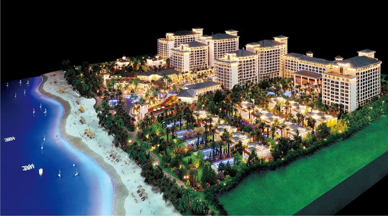 Model of a coastal resort with low-rise buildings and a sandy beach, lit at night