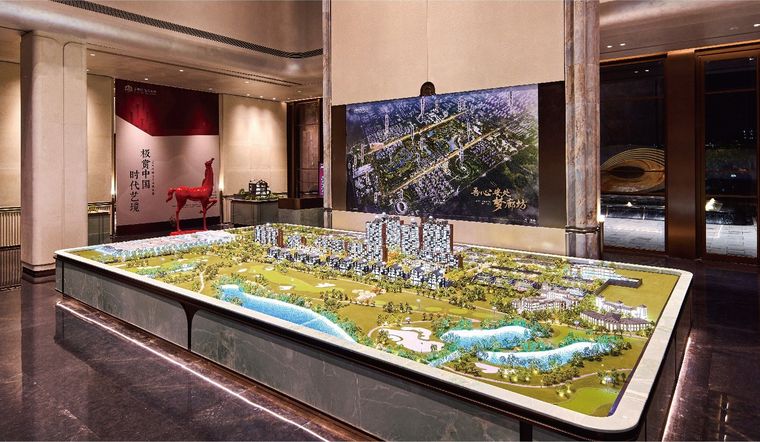 Model of an extended residential project before a photographic wall in a sales gallery