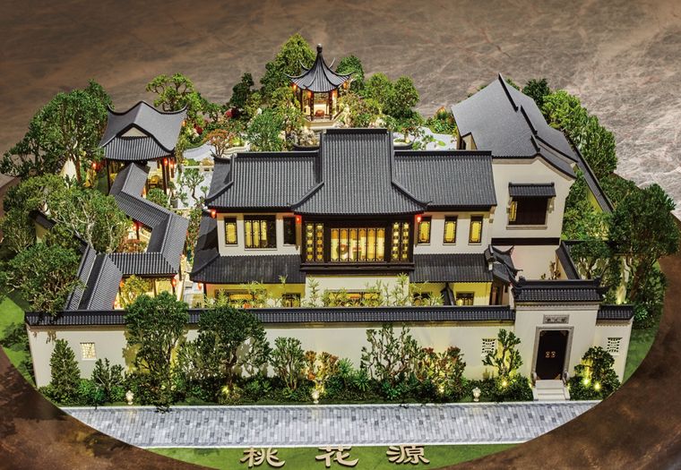 Heritage-style villa model lit at night with a front garden